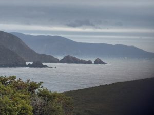 Misty Australian coastline with rock formations sharp in the foreground fading into a hazy, indistinct headland in the distance