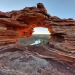 Ancient rock arch framing distant light — shaped over time, the grief of living someone else's truth and what becomes visible