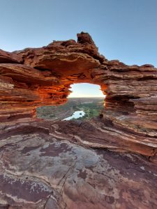 Ancient rock arch framing distant light — shaped over time, the grief of living someone else's truth and what becomes visible